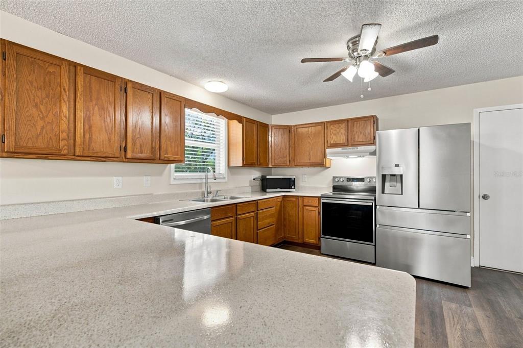 A kitchen with wood cabinets, stainless steel appliances, and light-colored countertops — 10380 GOLDEN AVENUE, WEEKI WACHEE, FL