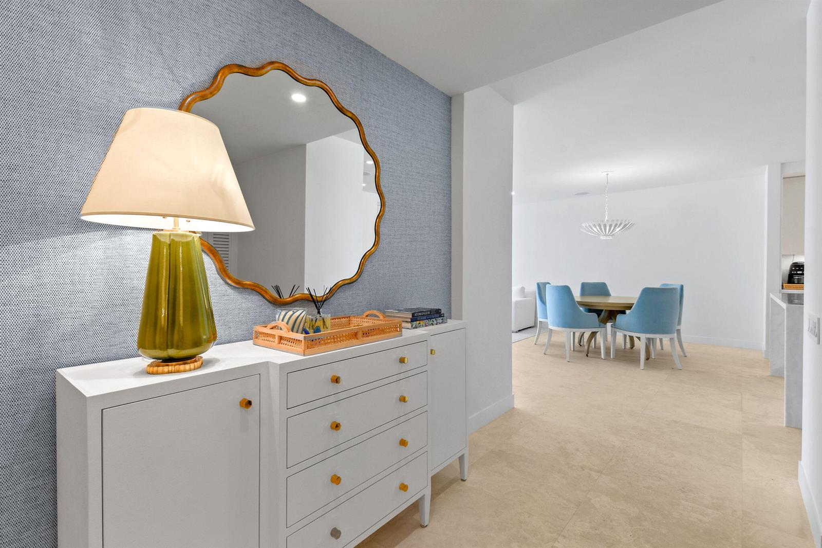 A white sideboard with a lamp and mirror sits against a blue textured wall — 2180 Ibis Isle Road # 12, Palm Beach FL 33480, PALM BEACH, FL