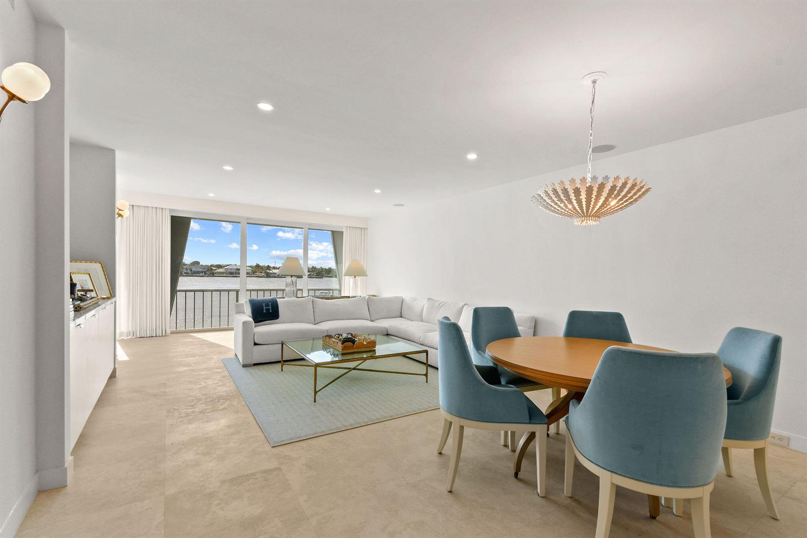 A bright, open-concept living and dining area features white walls, tile floors, and water views — 2180 Ibis Isle Road # 12, Palm Beach FL 33480, PALM BEACH, FL