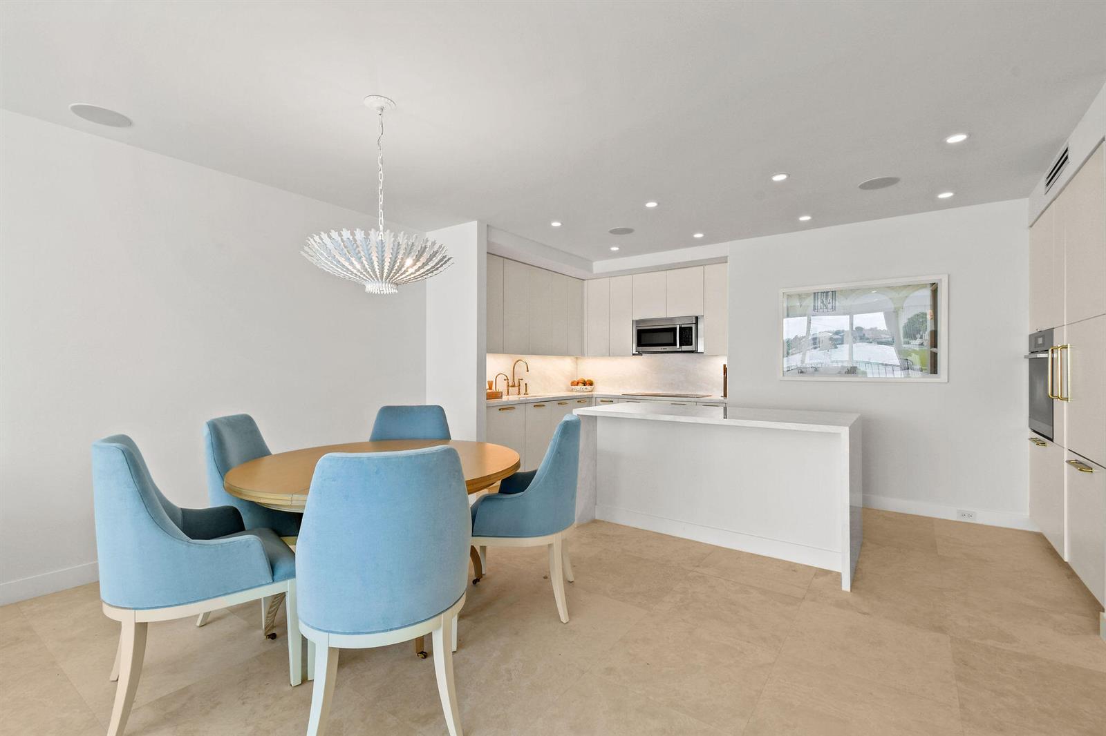 A modern kitchen and dining area with light blue chairs, a round table, and white cabinetry — 2180 Ibis Isle Road # 12, Palm Beach FL 33480, PALM BEACH, FL