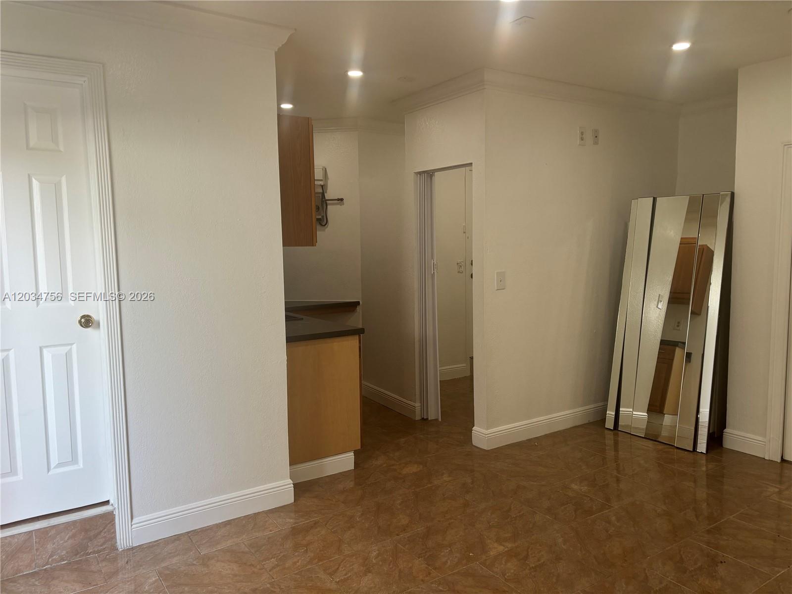 A tiled room features a white door, a kitchen corner, and a large floor mirror — 17811 SW 152nd Pl, Miami FL 33187, MIAMI, FL
