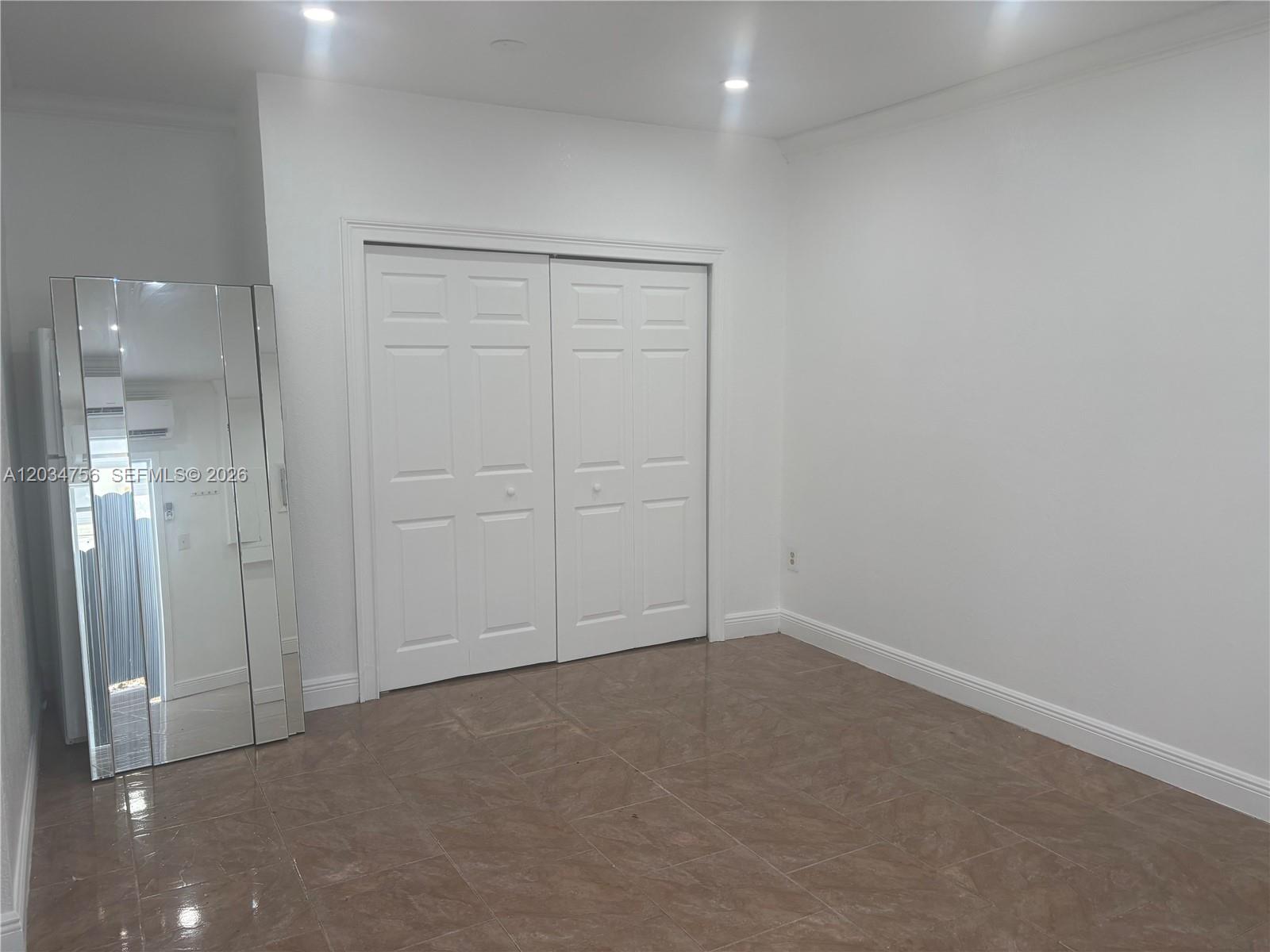 A room with white walls, tiled flooring, and a set of white closet doors — 17811 SW 152nd Pl, Miami FL 33187, MIAMI, FL