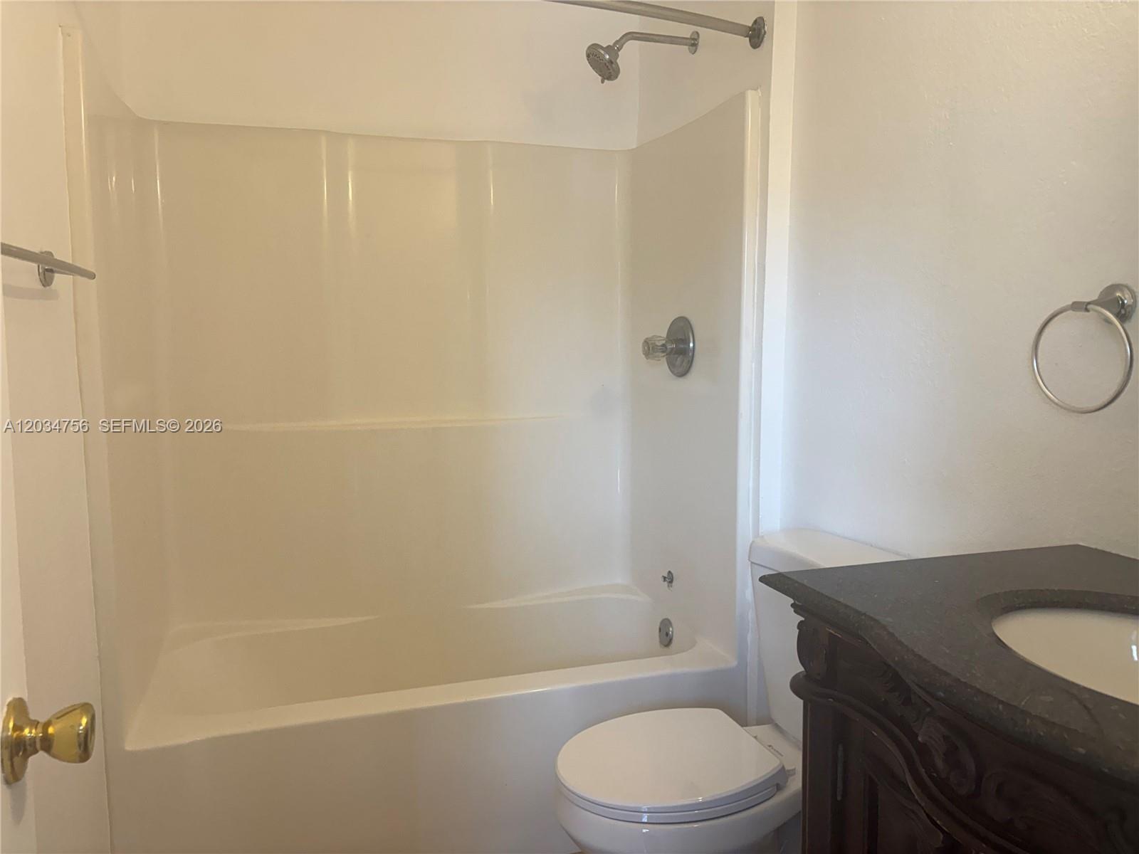 A bathroom features a white tub-shower combination, a toilet, and a dark wood vanity — 17811 SW 152nd Pl, Miami FL 33187, MIAMI, FL
