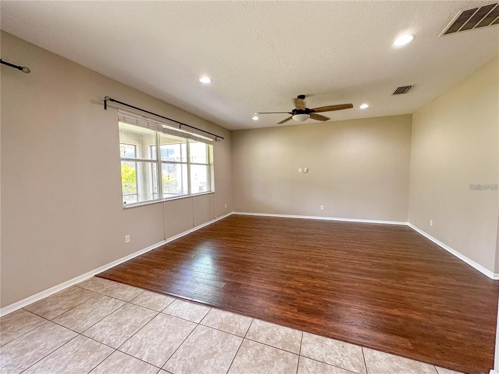 A living room features wood-look flooring, a ceiling fan, and a large window — 8979 39TH STREET CIRCLE E, PARRISH, FL
