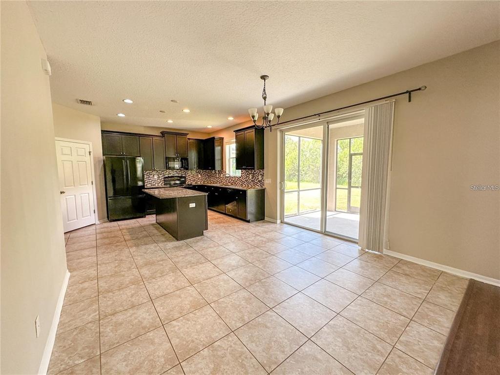 A kitchen with dark cabinets, a center island, and tile flooring opens to a patio — 8979 39TH STREET CIRCLE E, PARRISH, FL