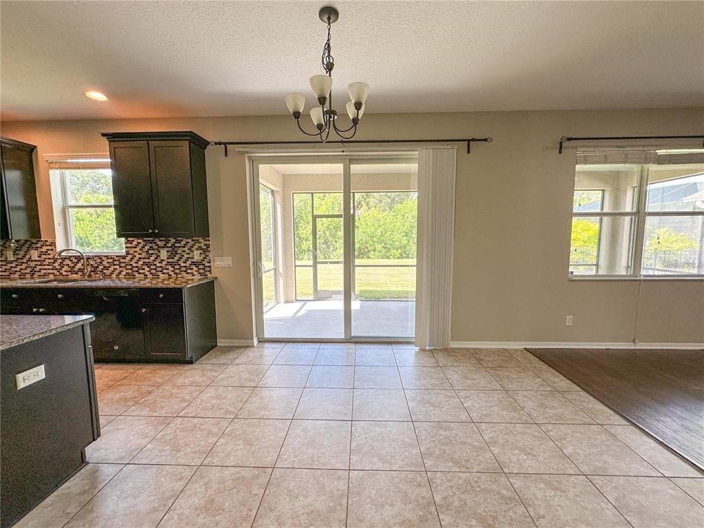 A kitchen with dark cabinets and tile flooring opens to a screened-in patio — 8979 39TH STREET CIRCLE E, PARRISH, FL