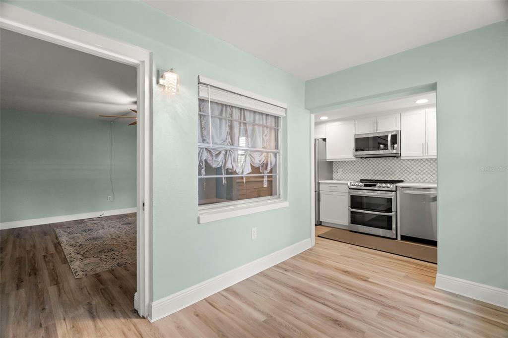 A dining area with light wood floors connects to a kitchen and a living room — 4780 COVE CIRCLE UNIT 205, ST PETERSBURG, FL