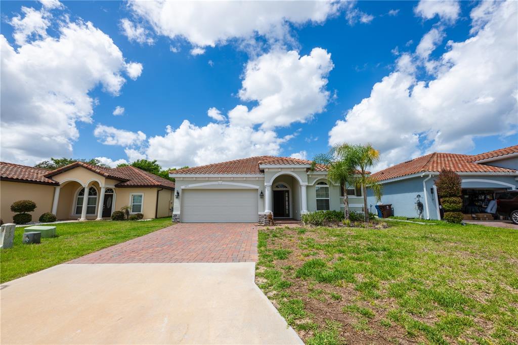 A single-story suburban house with a tile roof, brick driveway, and a two-car garage — 375 VILLA SORRENTO CIRCLE, HAINES CITY, FL
