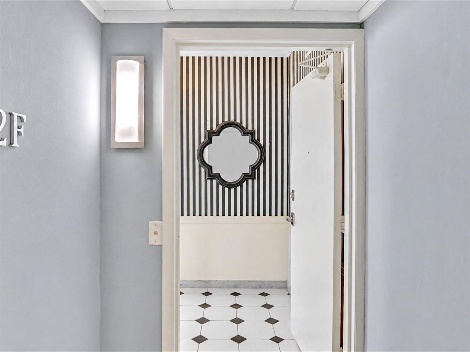 A doorway leads into an entryway with black and white striped wallpaper and tiled flooring — 50 East Road # 12f, Delray Beach FL 33483, DELRAY BEACH, FL