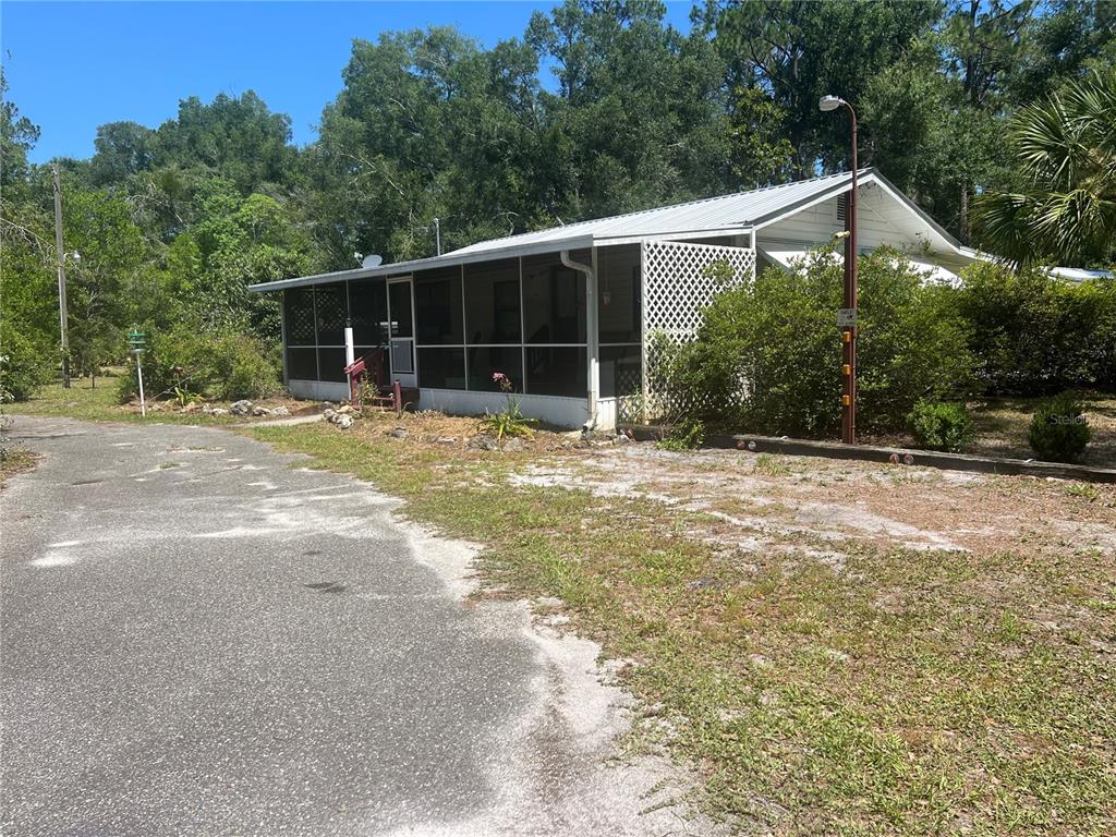 A single-story house with a metal roof and a large screened-in porch — 203 SE 45 AVENUE, CROSS CITY, FL