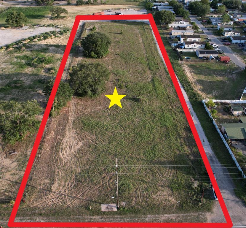 An aerial view shows a large, rectangular, grassy vacant lot outlined in red — 5645 JOHNSON AVENUE E, HAINES CITY, FL