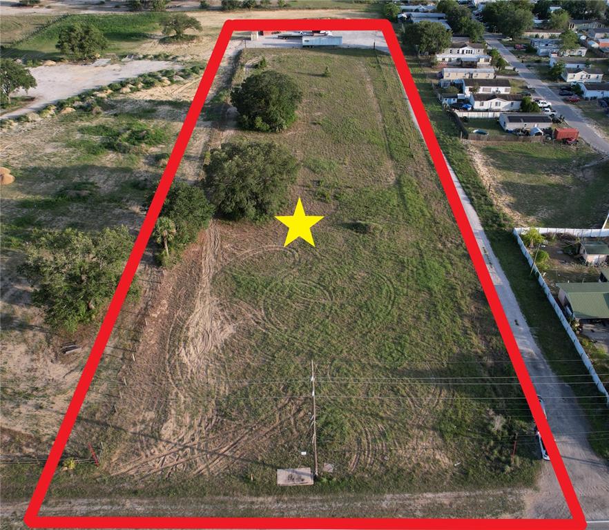 An aerial view shows a large, vacant, trapezoidal plot of land outlined in red — 5645 JOHNSON AVENUE E, HAINES CITY, FL