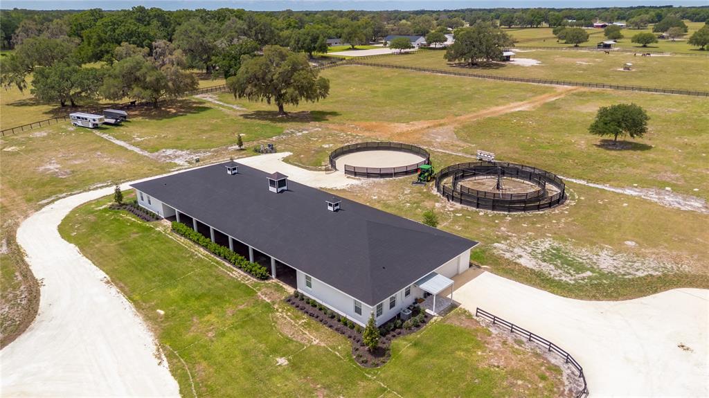 An aerial view shows a long white stable building with two circular horse training pens — 6170 NW 135TH AVENUE, MORRISTON, FL