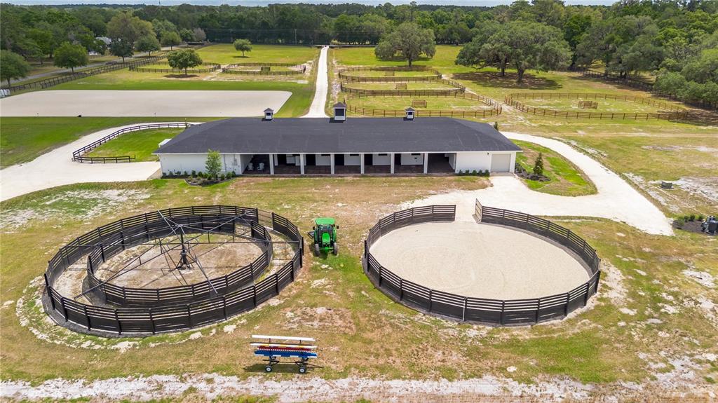 An aerial view shows a horse barn with a round pen and a horse walker — 6170 NW 135TH AVENUE, MORRISTON, FL