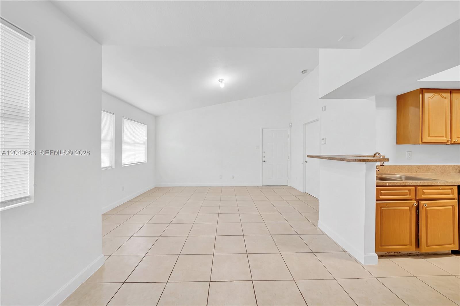 An open-concept living area features white walls, tile flooring, and an adjacent kitchen with cabinets — 15070 SW 103rd Ln # 2201, Miami FL 33196, MIAMI, FL