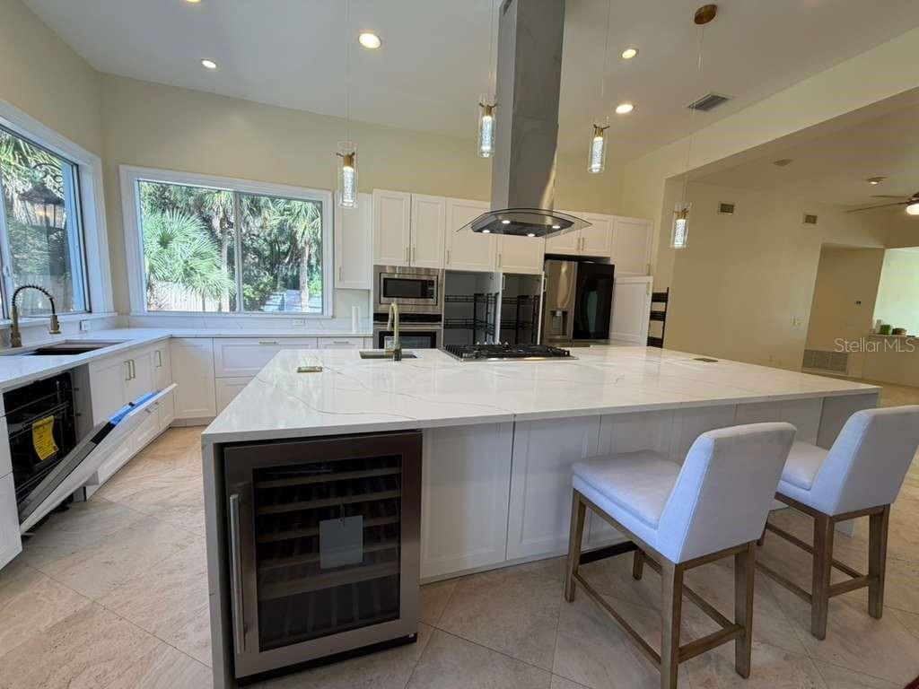 A modern kitchen features white cabinetry, a large marble island, and stainless steel appliances — 672 MOSSY BRANCH COURT, LONGWOOD, FL