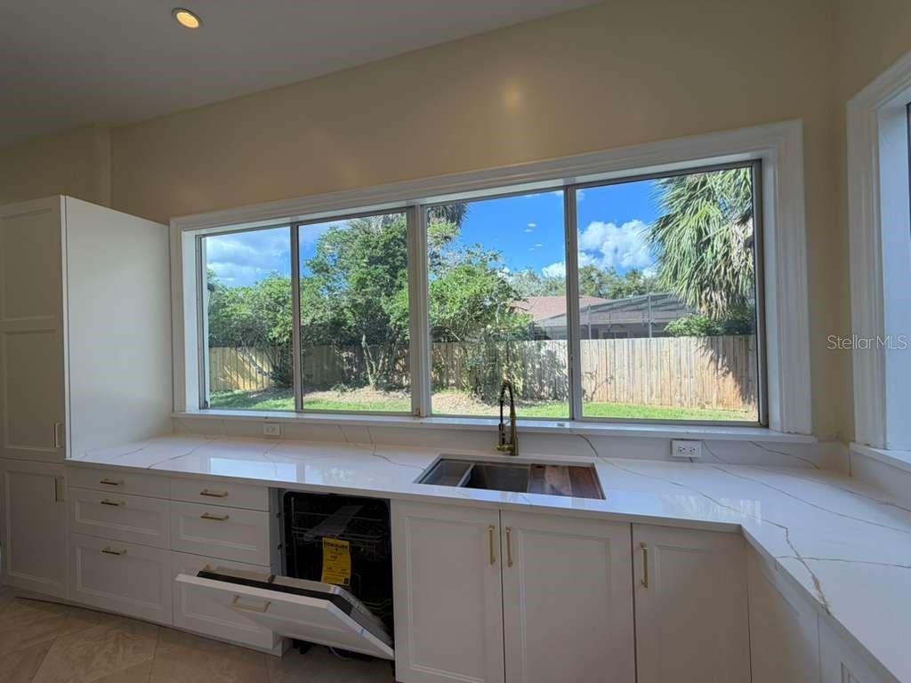 A kitchen features white cabinets, quartz countertops, a stainless steel sink, and a large window — 672 MOSSY BRANCH COURT, LONGWOOD, FL