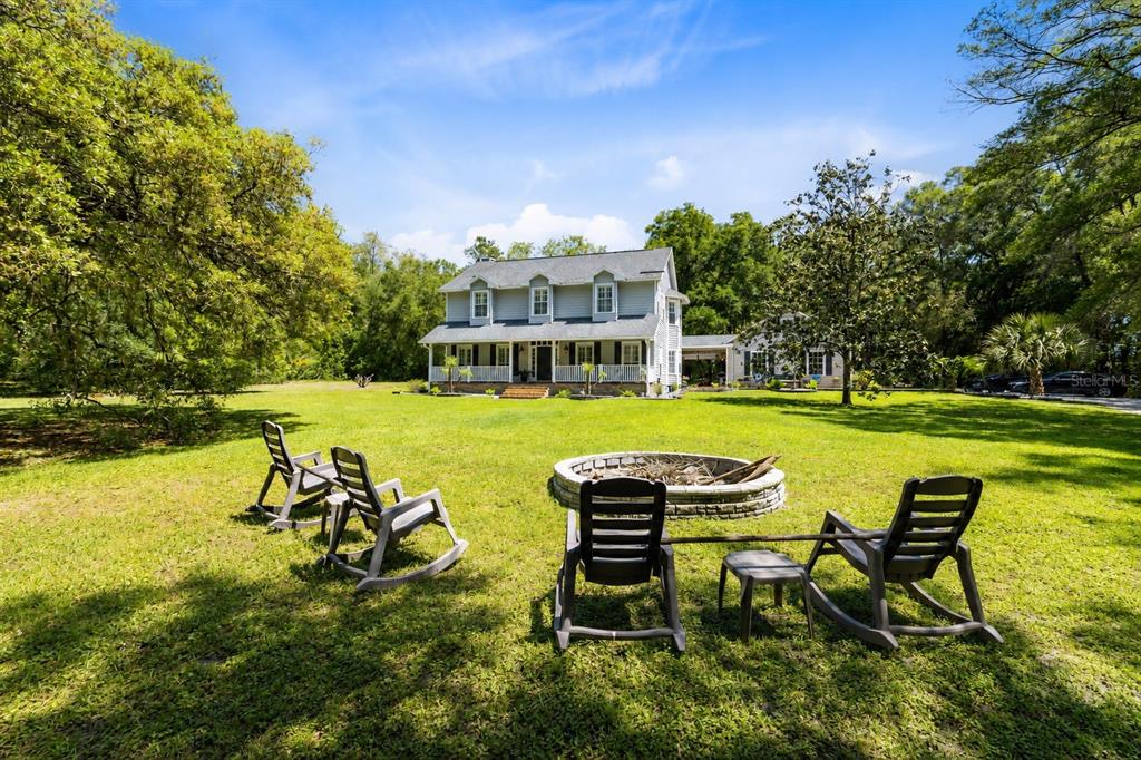 A two-story house with a large lawn, fire pit, and several rocking chairs — 5787 N APOPKA VINELAND ROAD, ORLANDO, FL