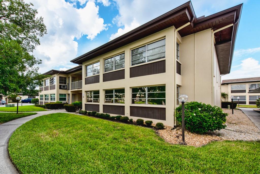 A two-story apartment building with beige stucco walls, dark brown trim, and large windows — 4826 MARINE PARKWAY UNIT 204, NEW PORT RICHEY, FL