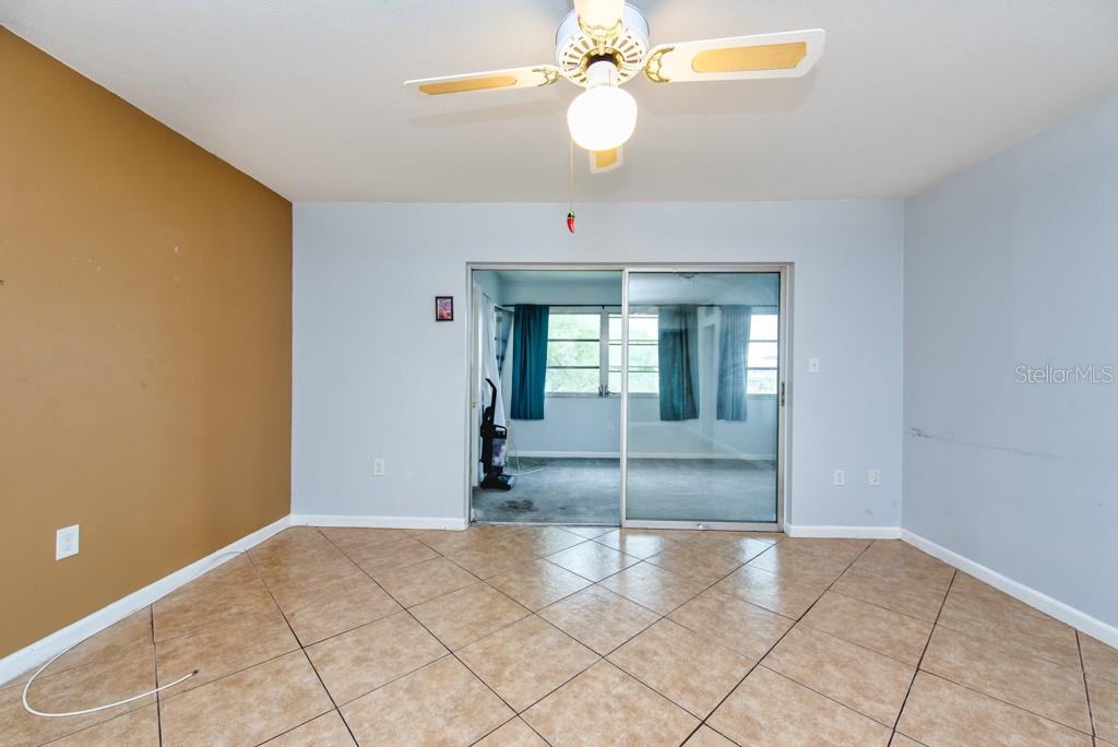 A room with tan tile flooring, a ceiling fan, and a sliding glass door — 4826 MARINE PARKWAY UNIT 204, NEW PORT RICHEY, FL