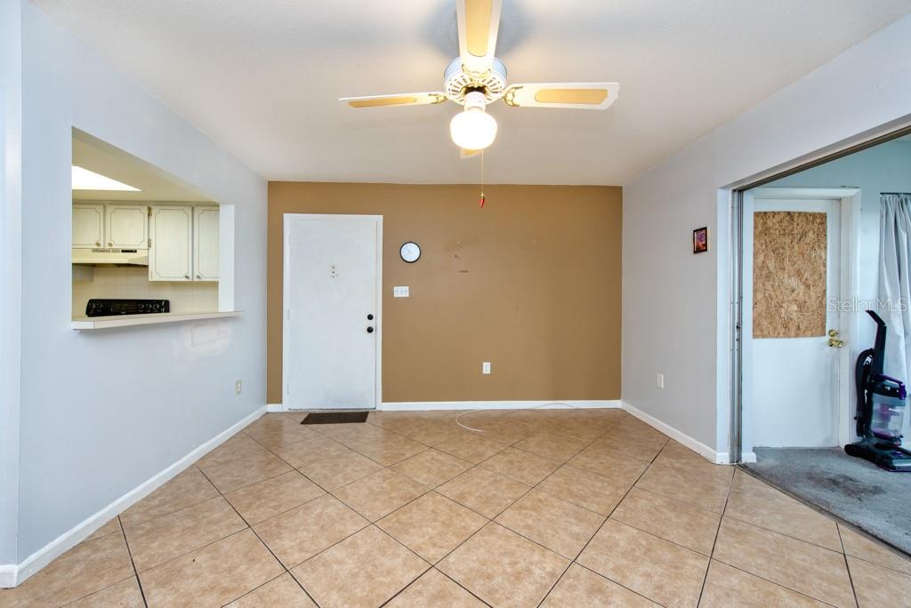 A dining area features tan tile flooring, a ceiling fan, and a brown accent wall — 4826 MARINE PARKWAY UNIT 204, NEW PORT RICHEY, FL