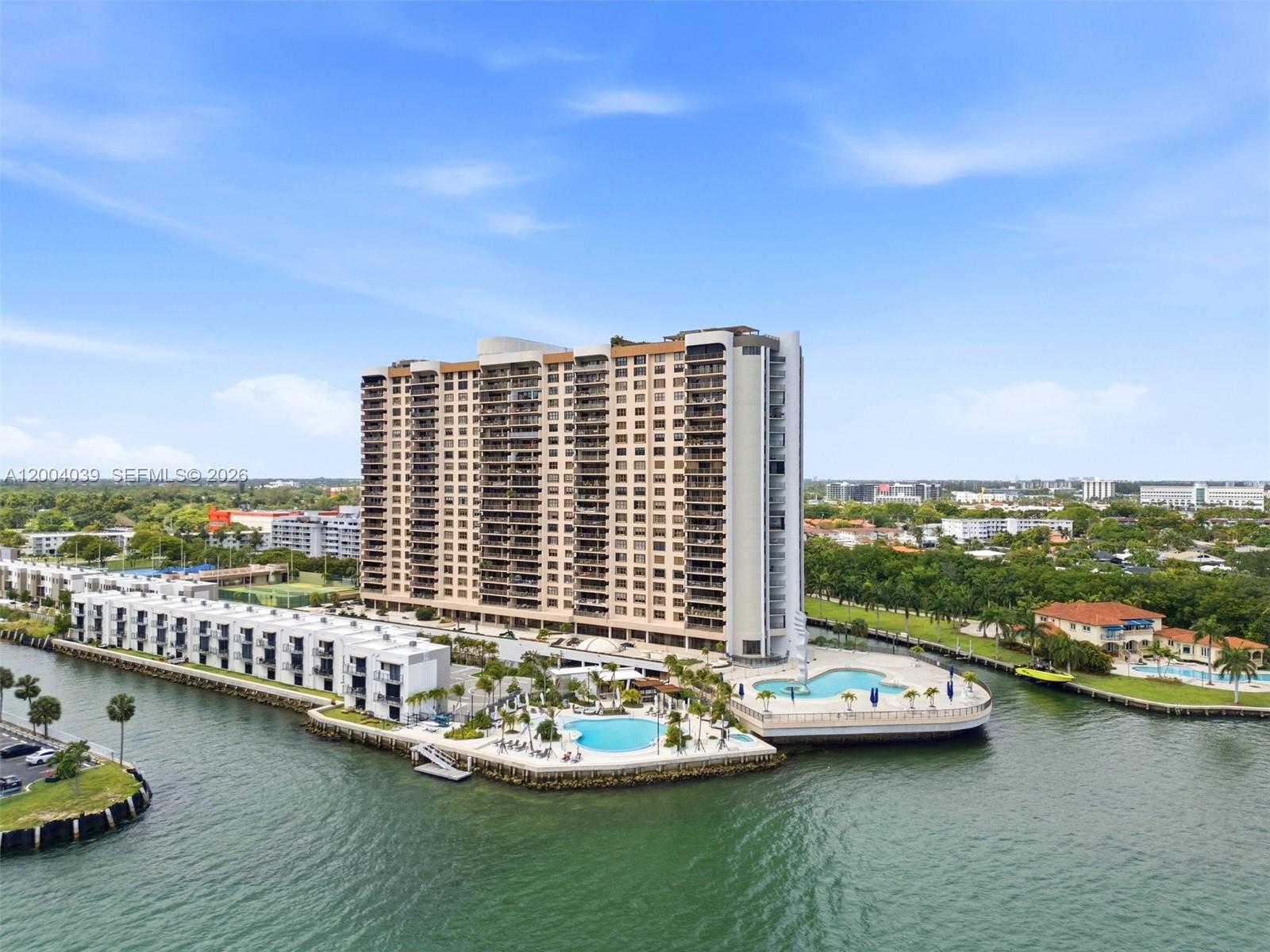 An aerial view shows a tall residential building with two swimming pools on a waterfront — 1800 NE 114th St # 1505, Miami FL 33181, MIAMI, FL