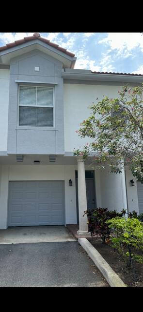 A two-story townhouse exterior features a gray garage door, a white column, and a window — 2036 Alta Meadows Lane # 1403, Delray Beach FL 33444, DELRAY BEACH, FL