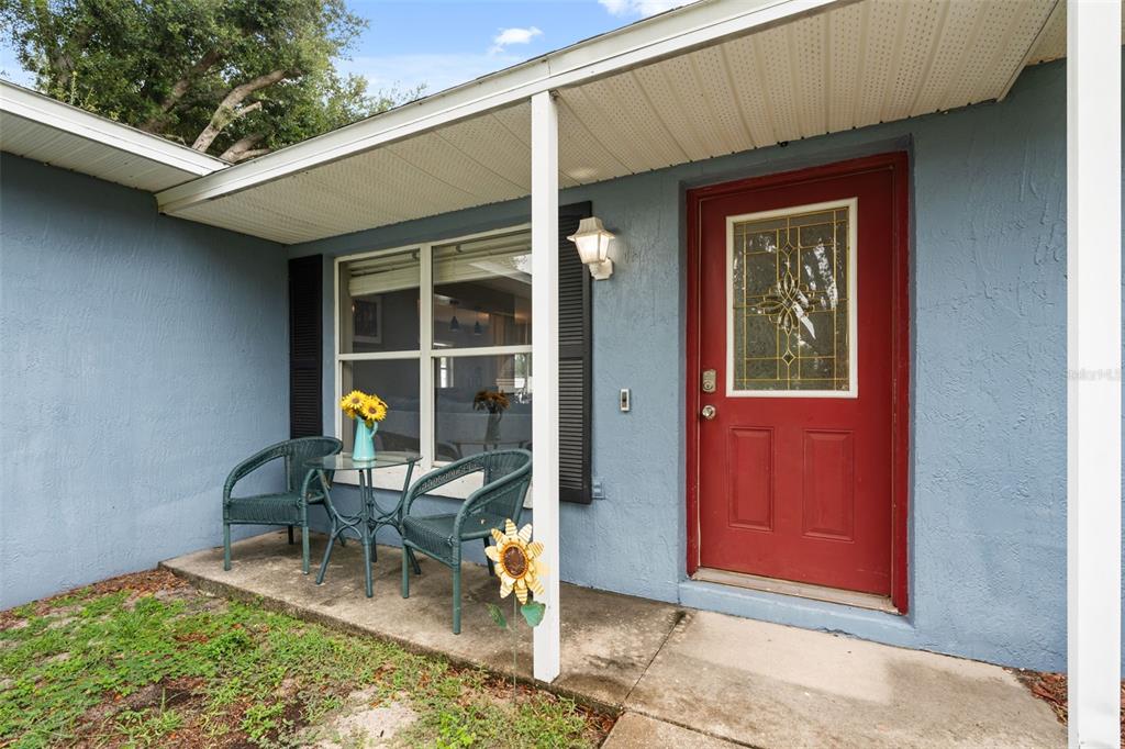 A blue house exterior features a red front door and a small patio with furniture — 503 DOROTHY CIRCLE, EUSTIS, FL