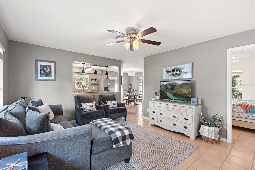 A living room with a gray sectional, two armchairs, a television, and tile flooring — 503 DOROTHY CIRCLE, EUSTIS, FL