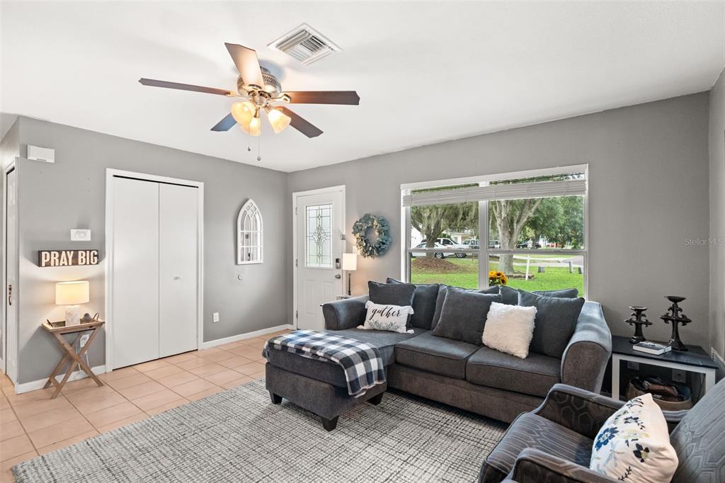 A living room features gray walls, tile flooring, a sectional sofa, and a ceiling fan — 503 DOROTHY CIRCLE, EUSTIS, FL