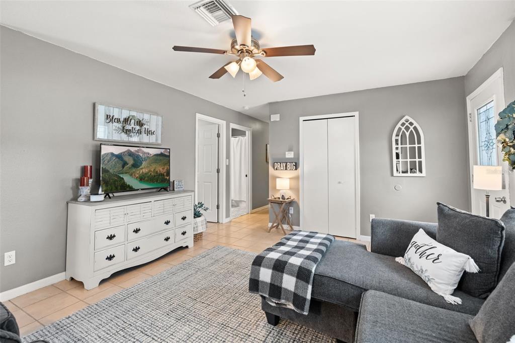A living room features a grey sofa, a white dresser with a television, and tile flooring — 503 DOROTHY CIRCLE, EUSTIS, FL