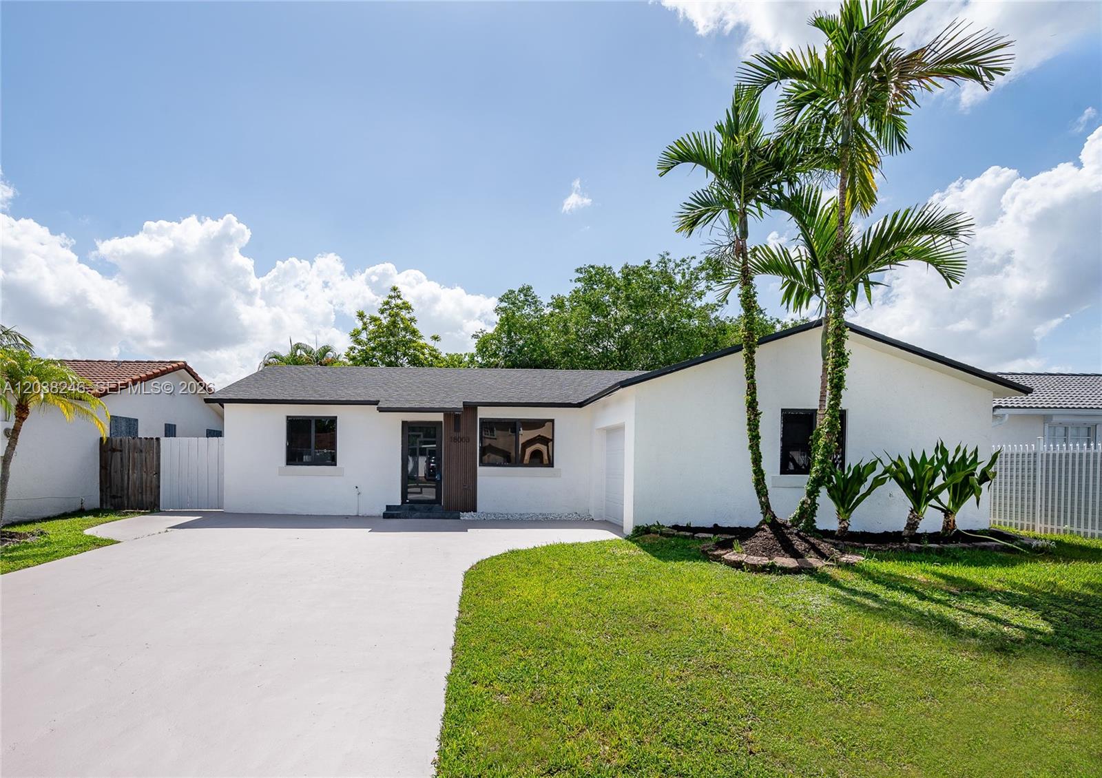 A white single-story house features a concrete driveway, palm trees, and a dark roof — MIAMI, FL