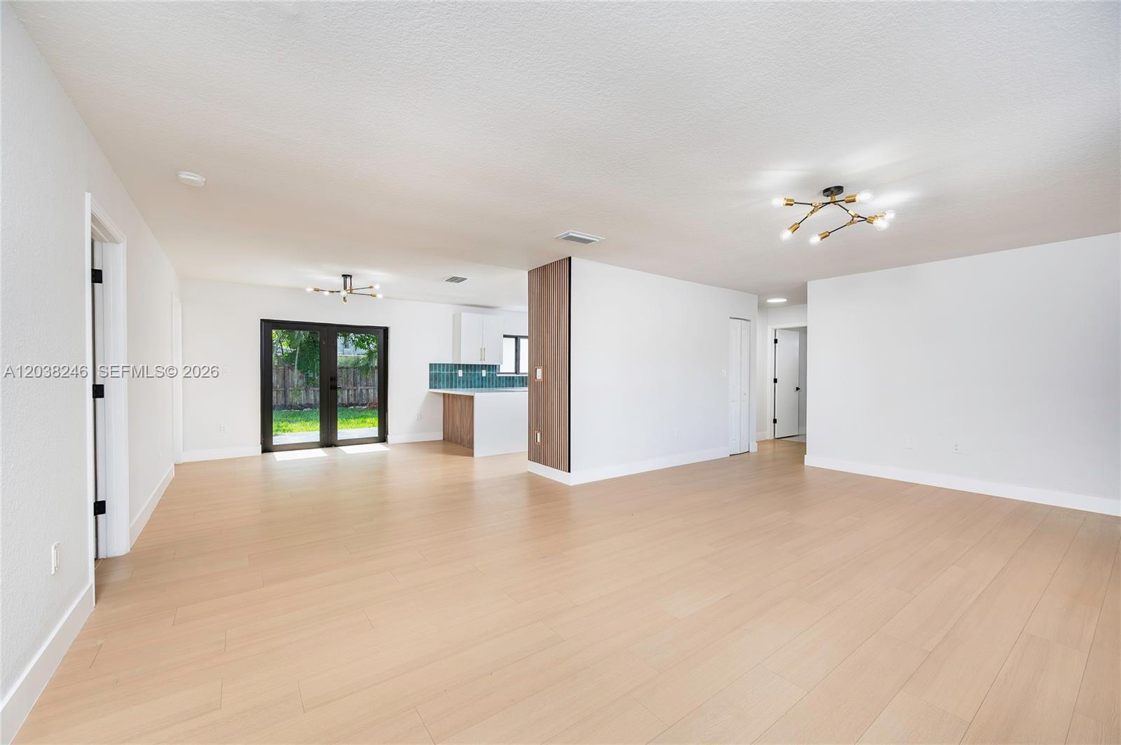 An open-concept living area features light wood flooring, white walls, and a modern kitchen — MIAMI, FL