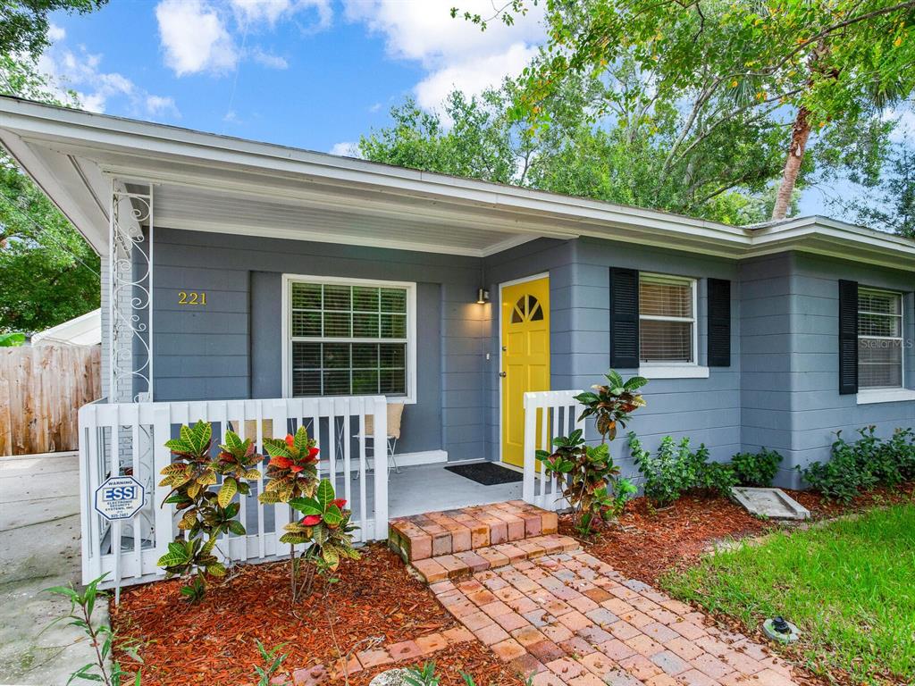 A gray house with a yellow front door and a brick walkway leading to the porch — 221 N CLEARVIEW AVENUE, TAMPA, FL