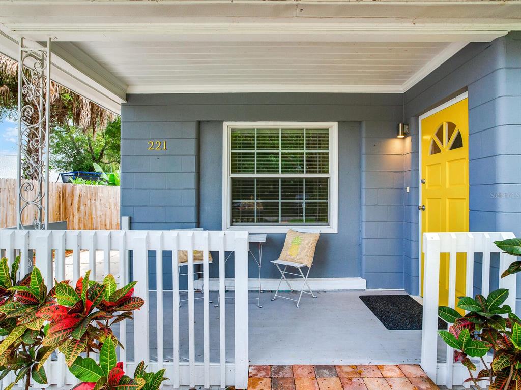 A front porch with a yellow door, white railing, and a window on a gray house — 221 N CLEARVIEW AVENUE, TAMPA, FL