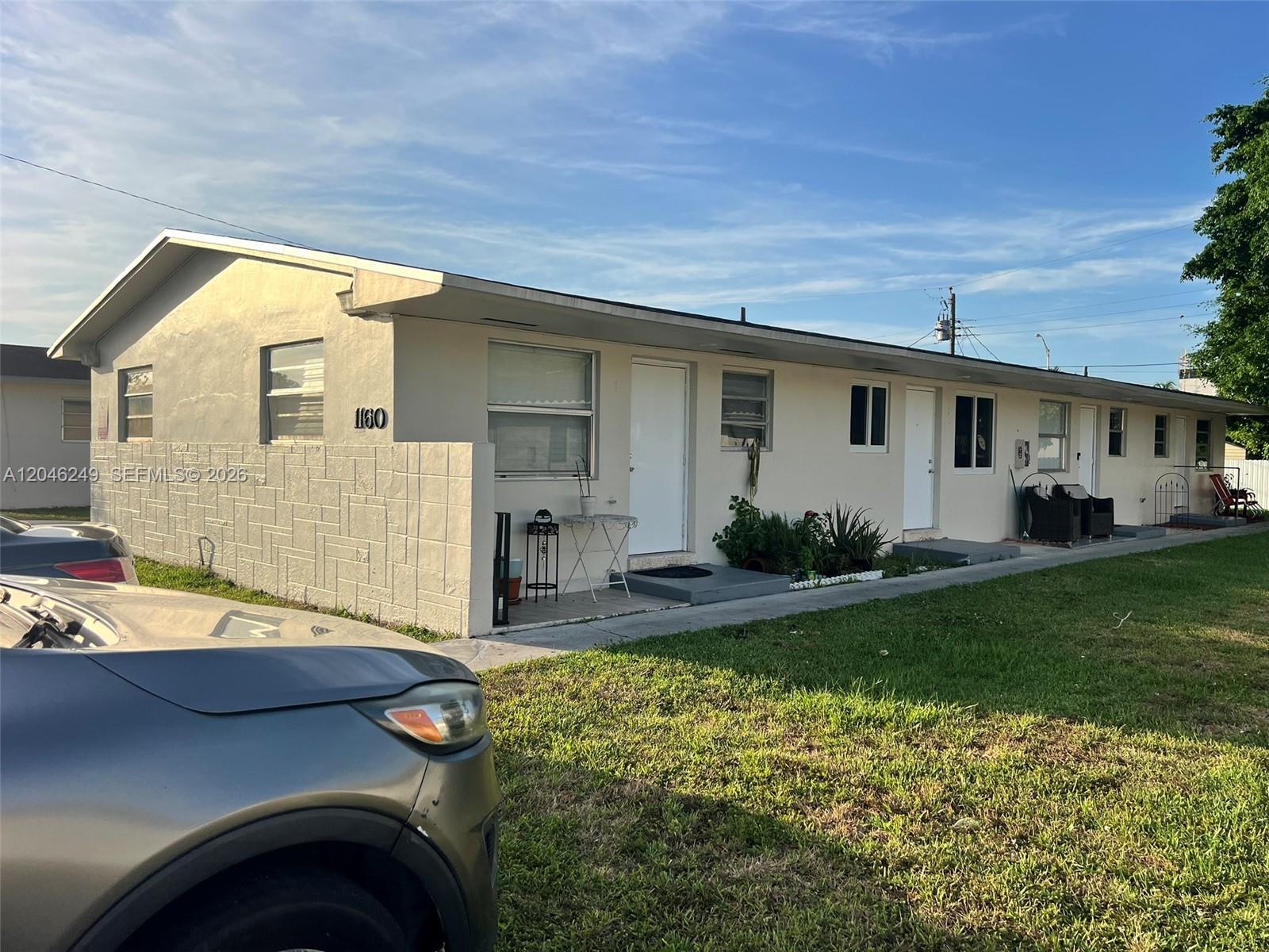 A single-story multi-unit residential building with a light-colored exterior and a grassy front yard — HIALEAH, FL