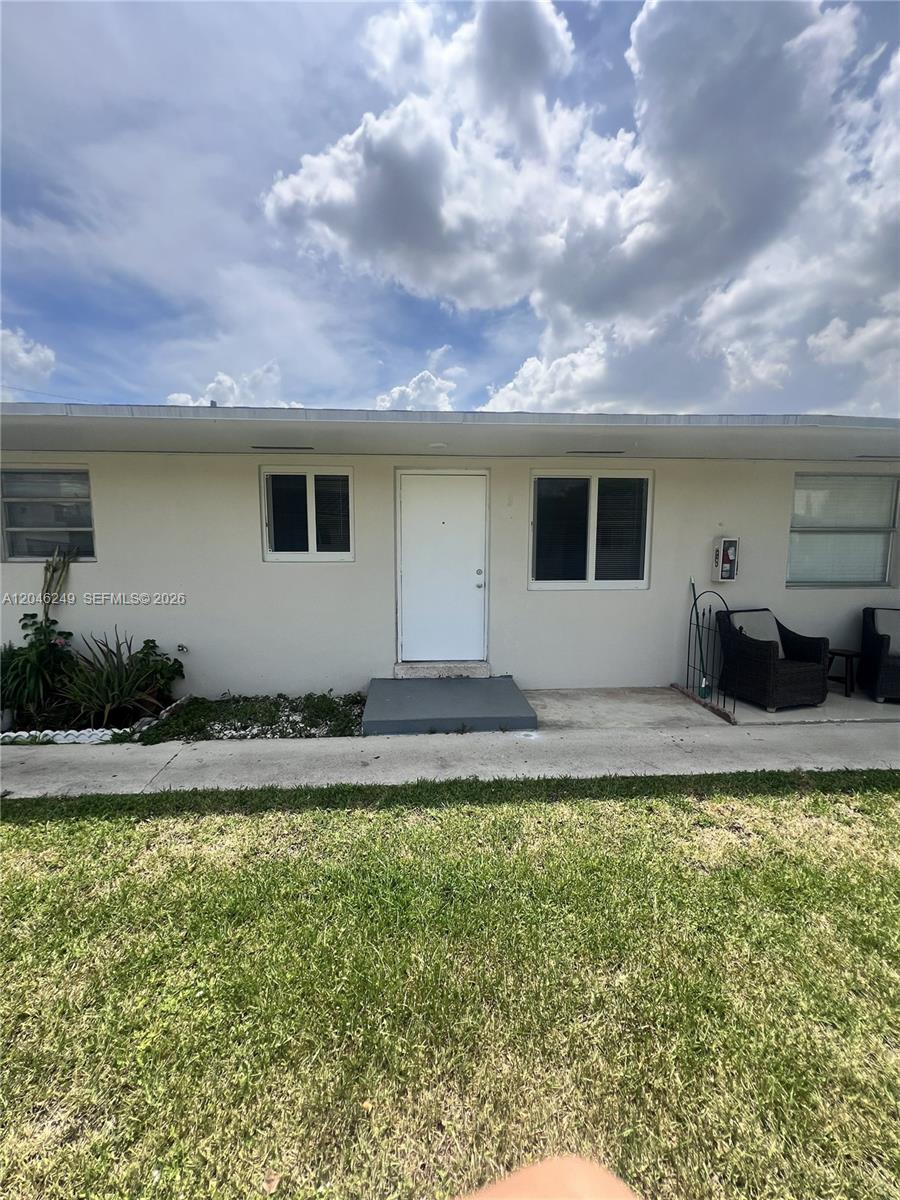 The exterior of a single-story building features a white door, windows, and a concrete walkway — HIALEAH, FL