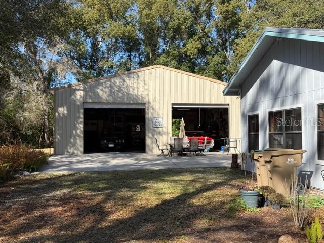 A detached metal garage with two open bays sits next to a residential house — 23404 HOBDY ROAD, SORRENTO, FL