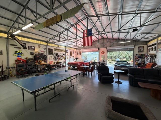 A large garage features a ping pong table, lounge seating, and a classic car — 23404 HOBDY ROAD, SORRENTO, FL