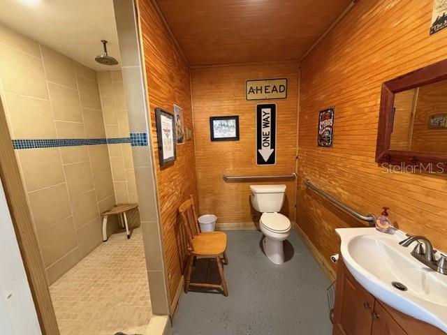 A bathroom features wood-paneled walls, a walk-in tiled shower, a toilet, and a pedestal sink — 23404 HOBDY ROAD, SORRENTO, FL