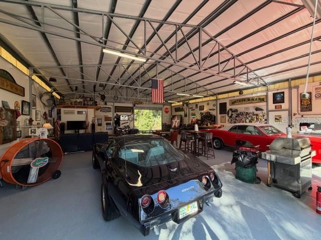 A spacious garage features a black Corvette, a red convertible, and various workshop equipment — 23404 HOBDY ROAD, SORRENTO, FL