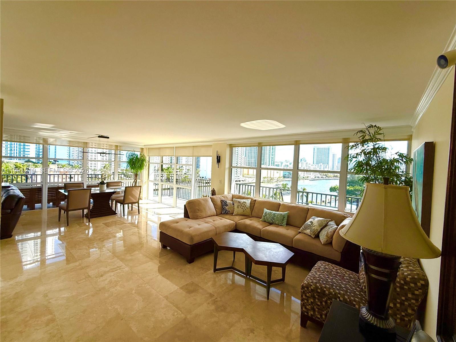 A living and dining area with marble floors, a sectional sofa, and floor-to-ceiling windows — 1000 Parkview Dr # 720, Hallandale Beach FL 33009, HALLANDALE BEACH, FL
