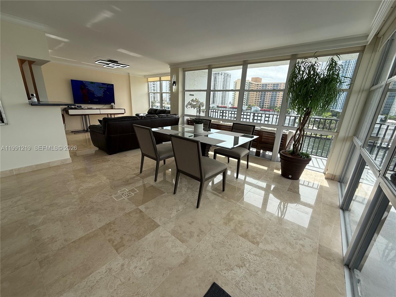 A dining area with a glass table and tile floors overlooks a balcony and city buildings — 1000 Parkview Dr # 720, Hallandale Beach FL 33009, HALLANDALE BEACH, FL