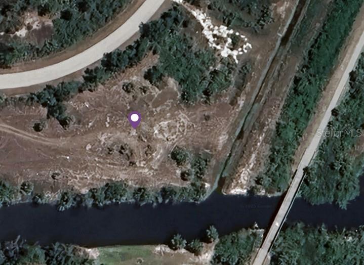 This aerial view shows a vacant, undeveloped lot bordered by a road and a canal — 7648 ST REGIS CIRCLE, PORT CHARLOTTE, FL