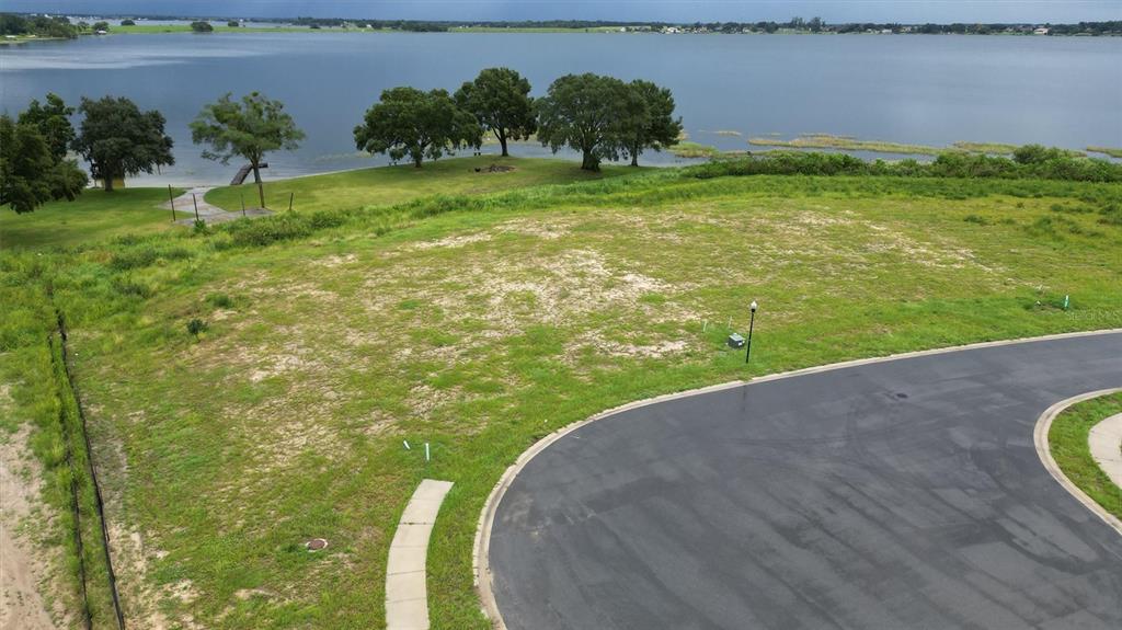 An elevated view of a vacant, grassy residential lot overlooking a lake — 1105 ENCLAVE COURT, AUBURNDALE, FL