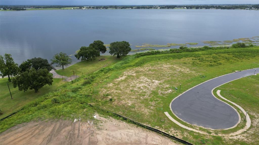 An aerial view shows a vacant lot with a cul-de-sac overlooking a large lake — 1105 ENCLAVE COURT, AUBURNDALE, FL