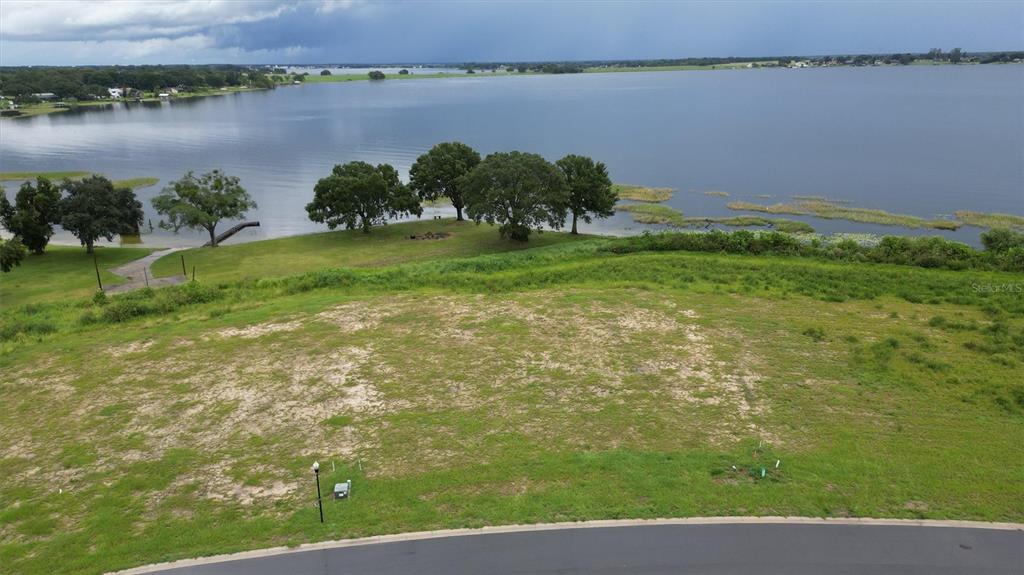 An elevated view of a grassy vacant lot overlooking a large lake with trees — 1105 ENCLAVE COURT, AUBURNDALE, FL