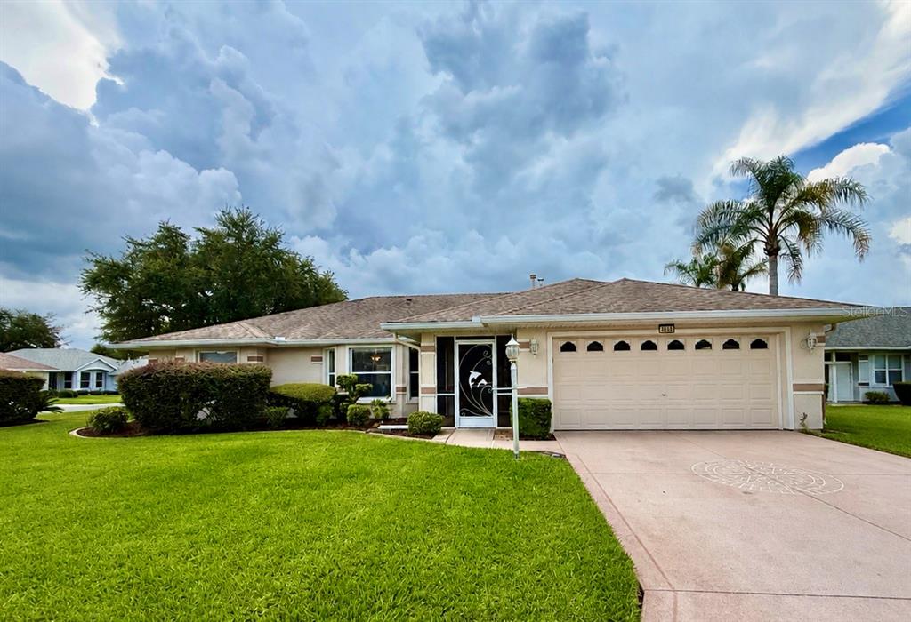 A single-story suburban house with a tan exterior, a two-car garage, and a green lawn — 4646 INVERNESS DRIVE, LEESBURG, FL