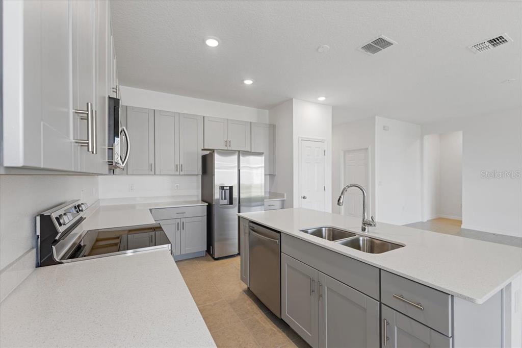 A kitchen features gray cabinets, white countertops, stainless steel appliances, and a central island — 519 SILVER PALM DRIVE, HAINES CITY, FL