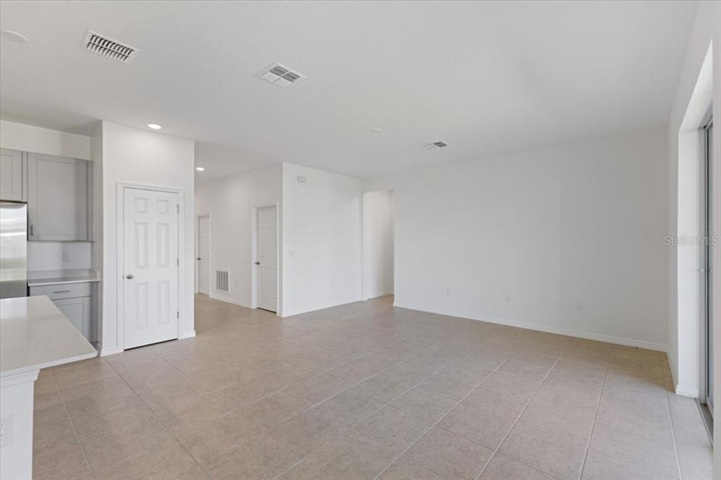 An open-concept living area features light-colored tile flooring, white walls, and a kitchen corner — 519 SILVER PALM DRIVE, HAINES CITY, FL